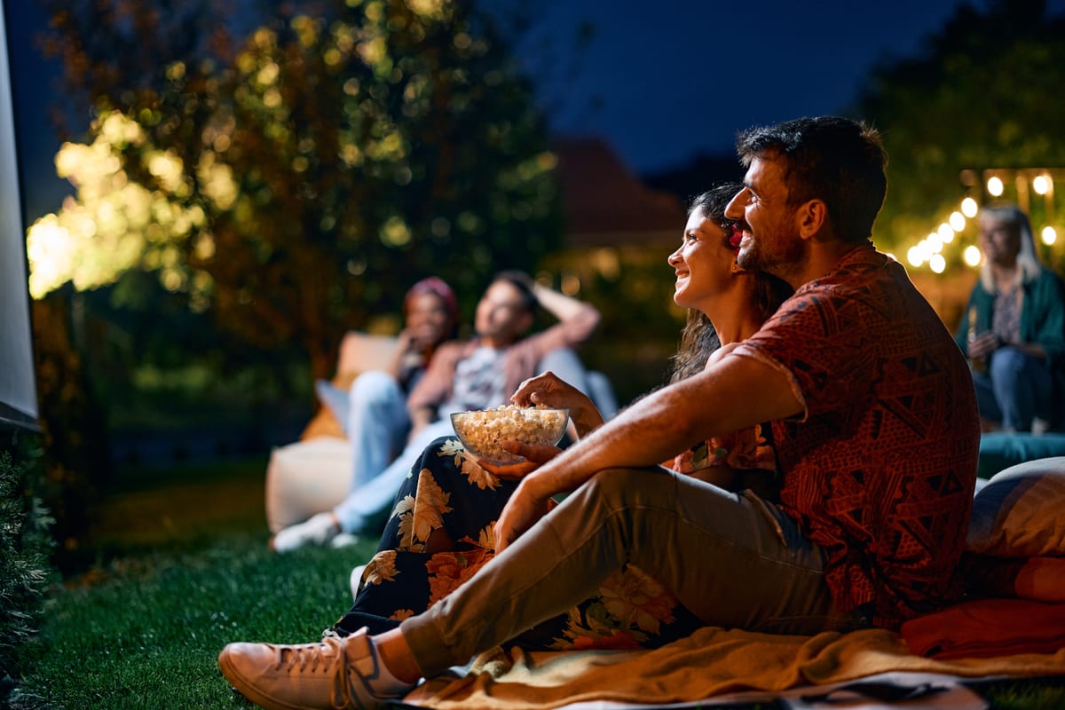 Outdoor Cinema hire — couple watching movie in backyard with friends | Panda Party Hire Hire outdoor cinema — couple watching movie in backyard with friends for parties and events in Johannesburg, Sandton and Randburg
